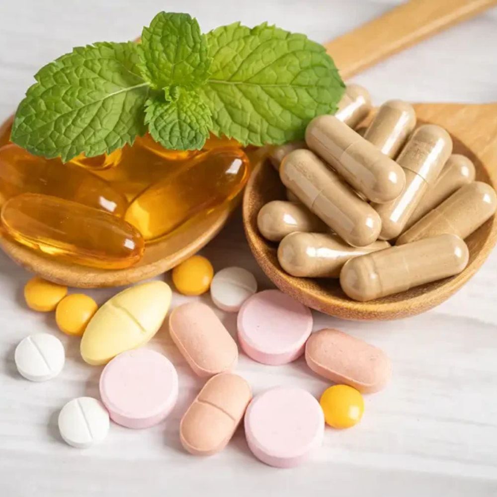 Assorted pills and capsules on a white background with mint leaves.